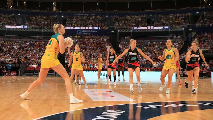 An Australian netballer shapes to pass the ball as she stands outside the two-point shot line.