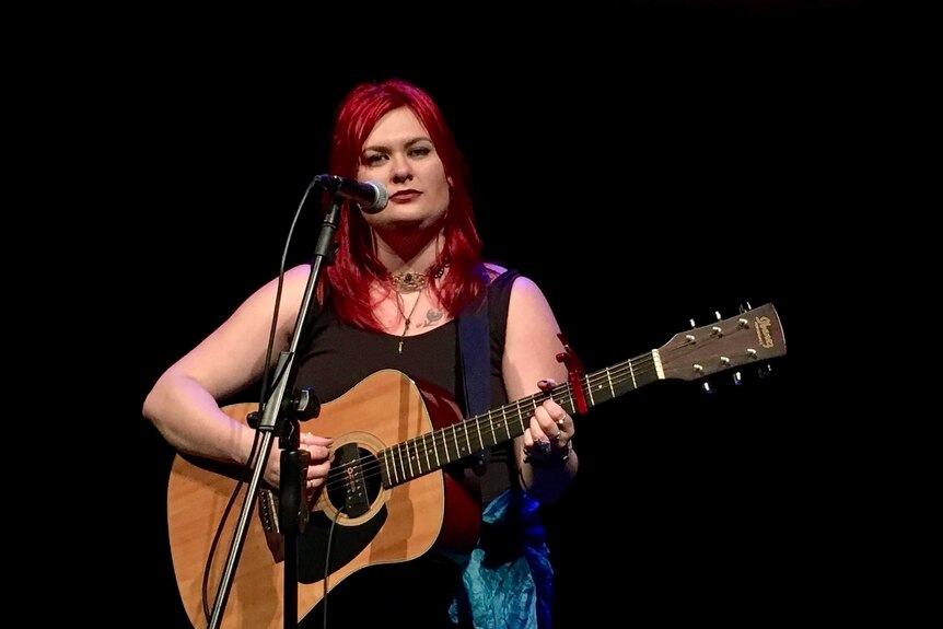 Cara Matthews plays guitar.