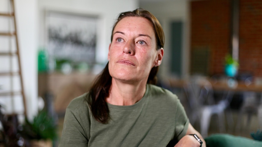 Michele Berry sits on a chair and leans on the back while looking away from the camera. 