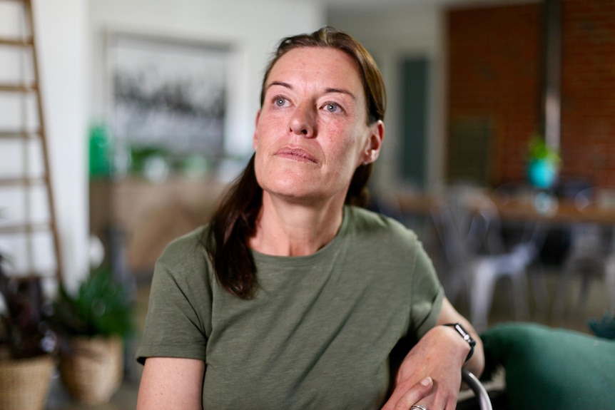 Michele Berry sits on a chair and leans on the back while looking away from the camera. 