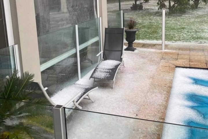 Hail on paving, in a pool and on the lawn at a house.