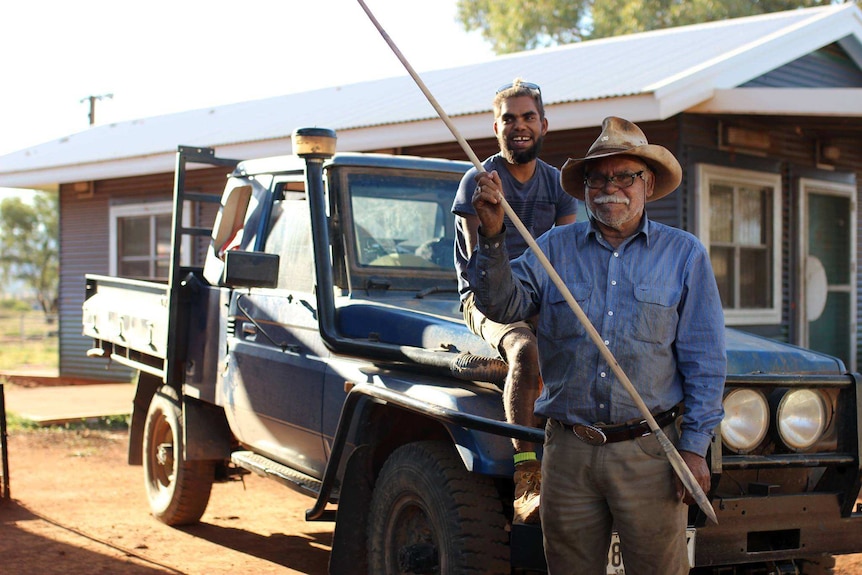 Artists Frank Young holds a spear while his nephew Anwar sits on the bonnet of a land cruiser