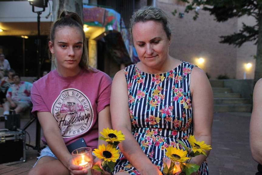 Mourners attend a vigil for a woman allegedly murdered at the Noarlunga shopping centre.