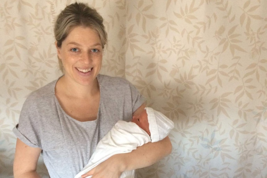 Nicola Goring holding her baby and smiling.