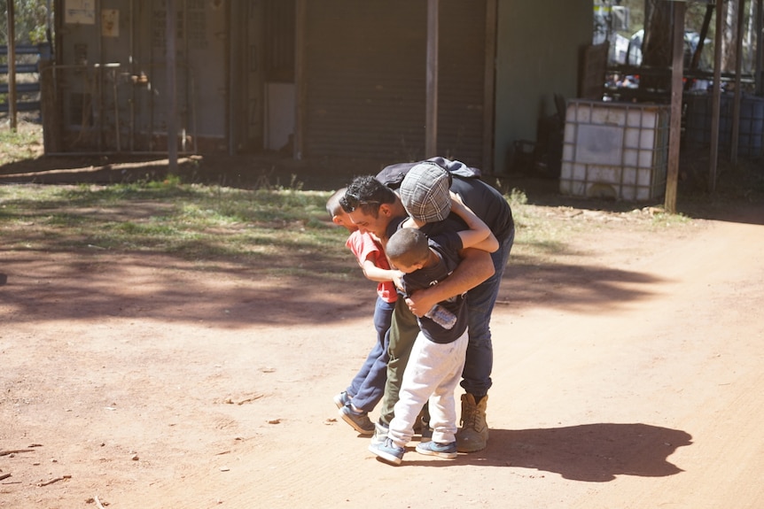 Man hugs three children.