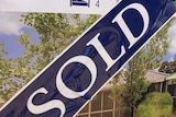 photo of a sold sticker over a real estate board