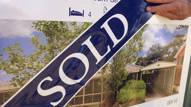 photo of a sold sticker over a real estate board