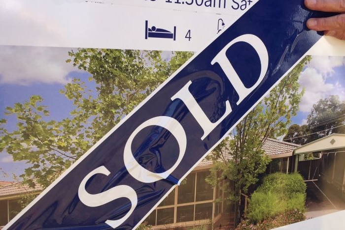 photo of a sold sticker over a real estate board