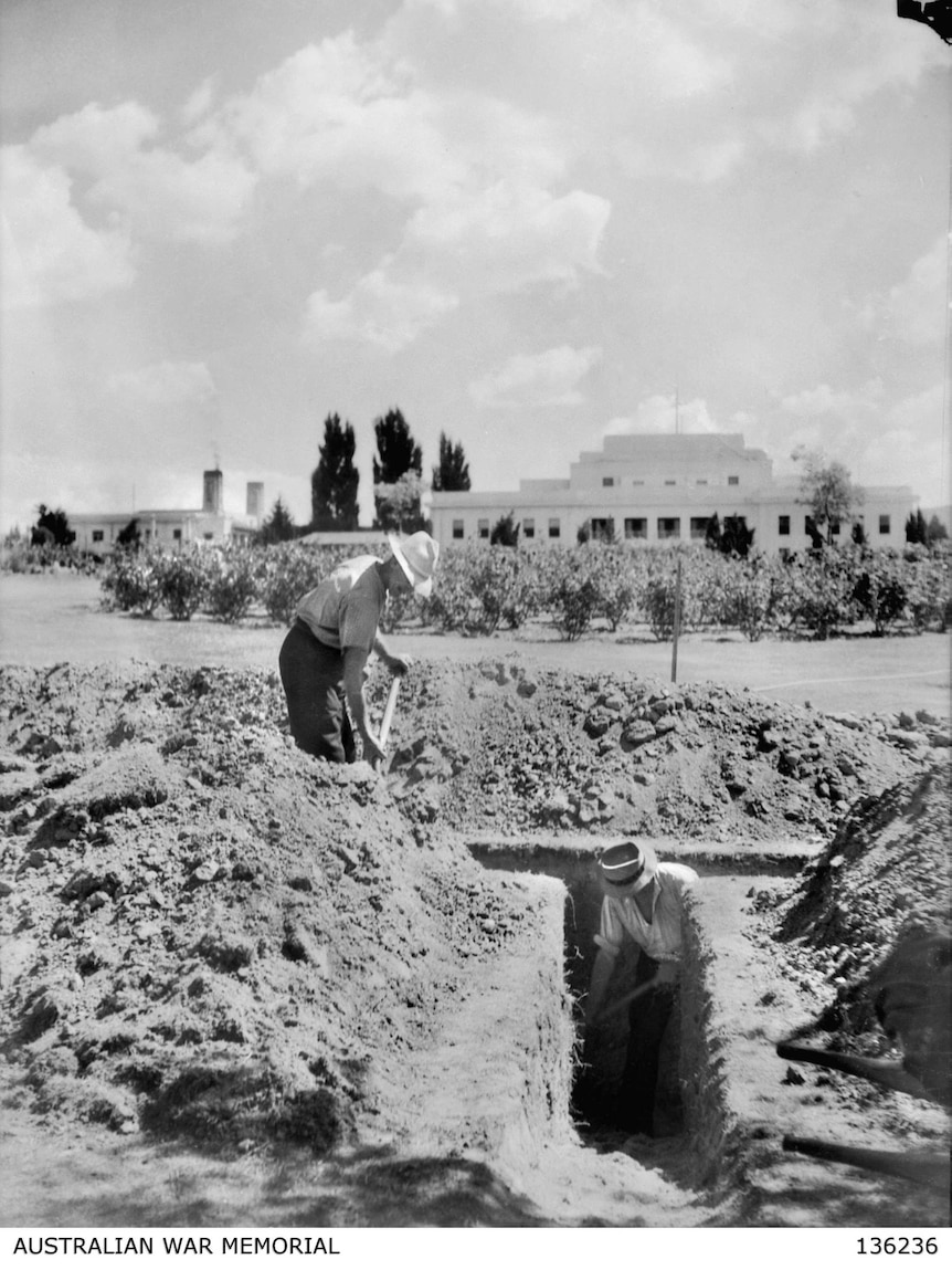Two men dig a trench outside Old Parliament House.