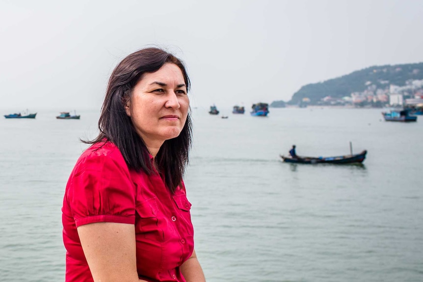 A woman in a red dress gazes over the water in Vietnam