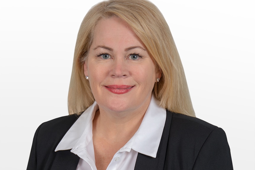 A blonde woman in a black jacked and white shirt.