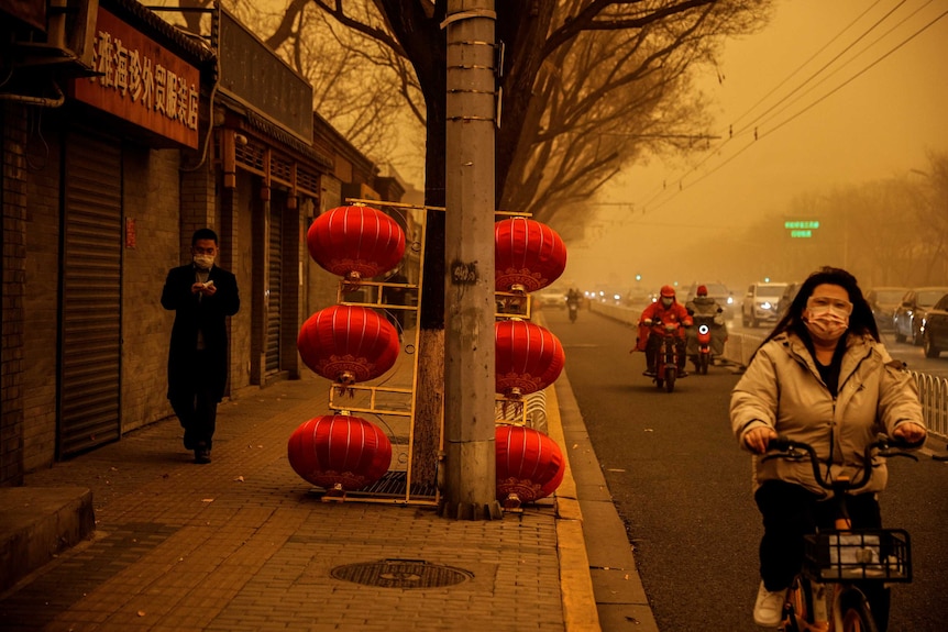 A woman rides a bike down a street covered in yellow smog