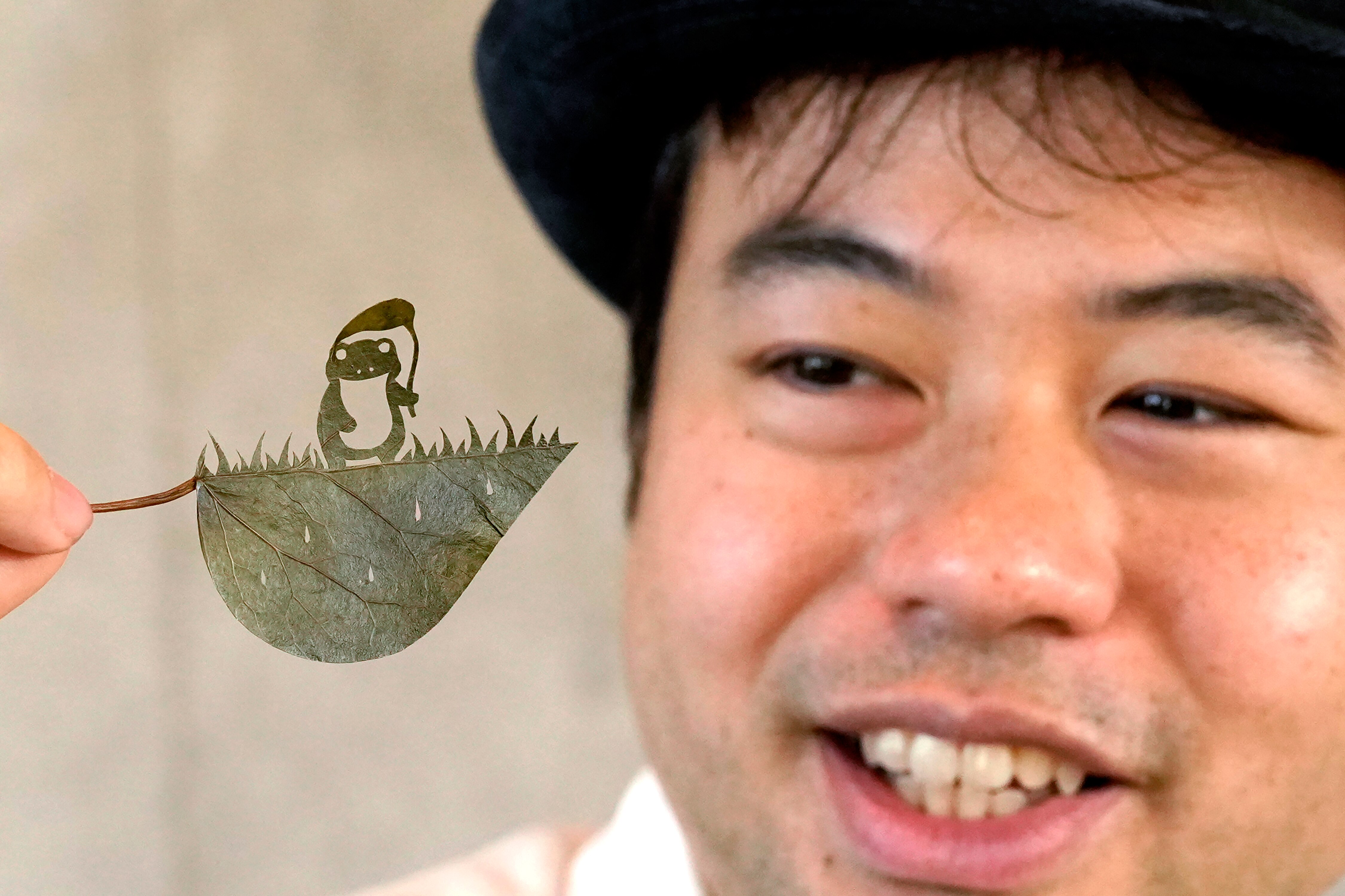 Japanese leaf-cutting artist, who goes by the name Lito, looks at his freshly cut work featuring a frog with an umbrellaAP24335052118455