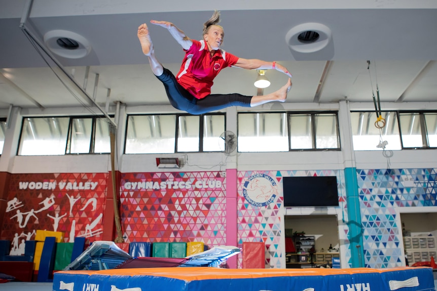 A woman leaps dramatically into the air while on a trampoline.
