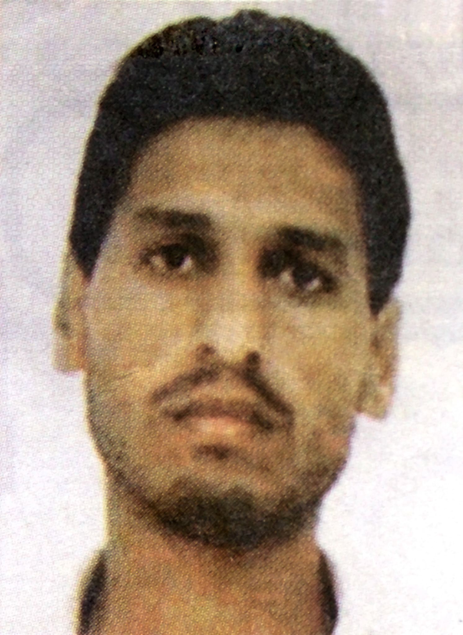 A close up, blurry photo of a man with a moustache and brown eyes.