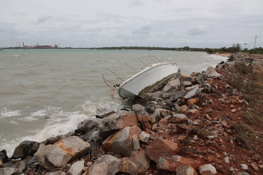 A boat is seen washed ashore in Nhulunbuy with the town's bauxite mine in the background.