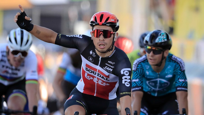 Caleb Ewan holds one hand in the air and points to the sky