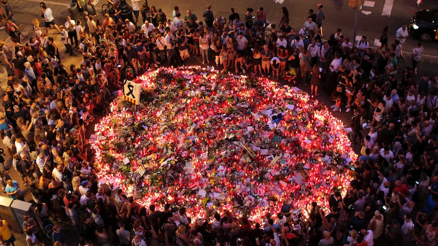 People pay respects at a growing memorial tribute on the Joan Miro mosaic on Las Ramblas.