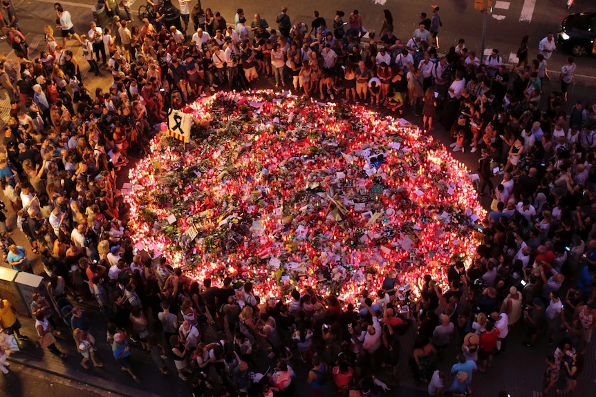 People pay respects at a growing memorial tribute on the Joan Miro mosaic on Las Ramblas.