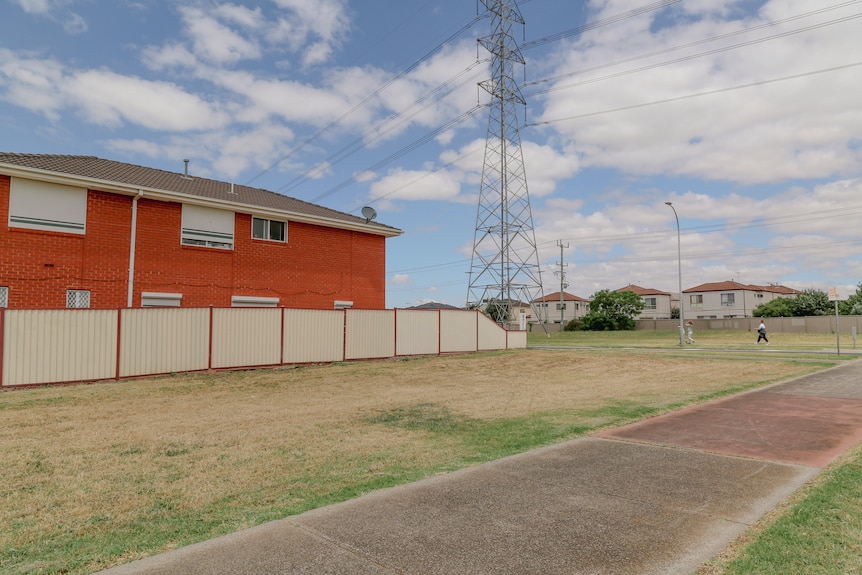 A two-storey brick home which is set behind a footpath with no tree cover