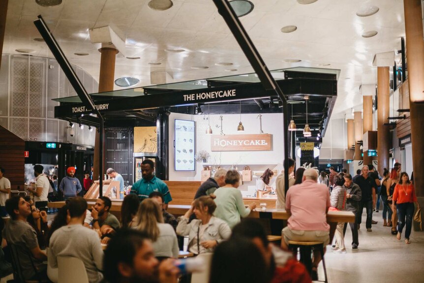 People seated dining at an indoor food hall at night