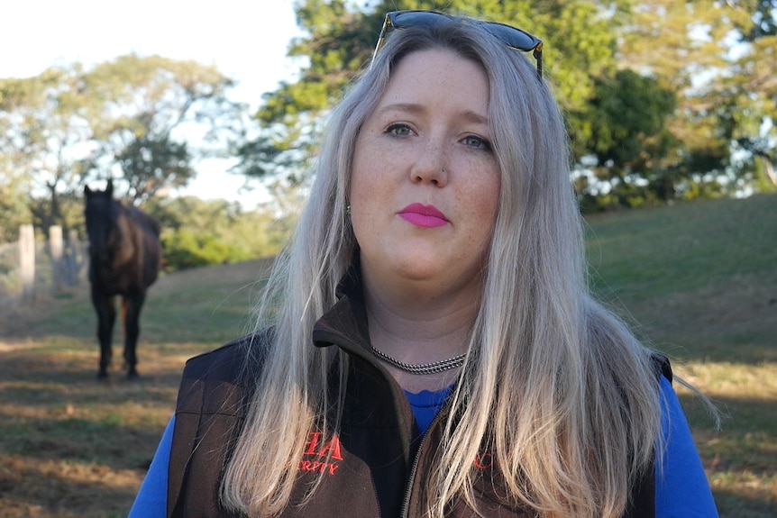 Zoe Wales stands in a paddock with her horse Jack.