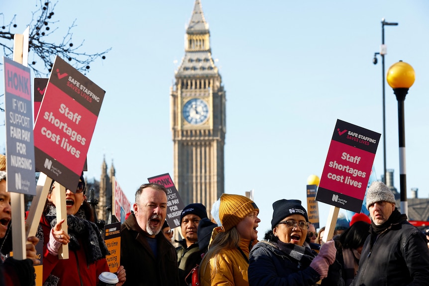 A group of protesters holding placards which read "staff shortages cost lives" with big ben clock tower in the background