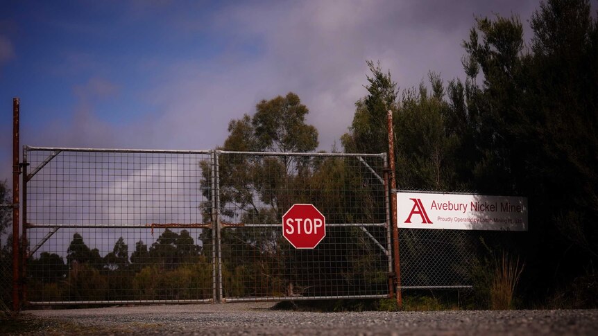 Locked gates with a stop sign at the entrance to the Avebury Nickel Mine.