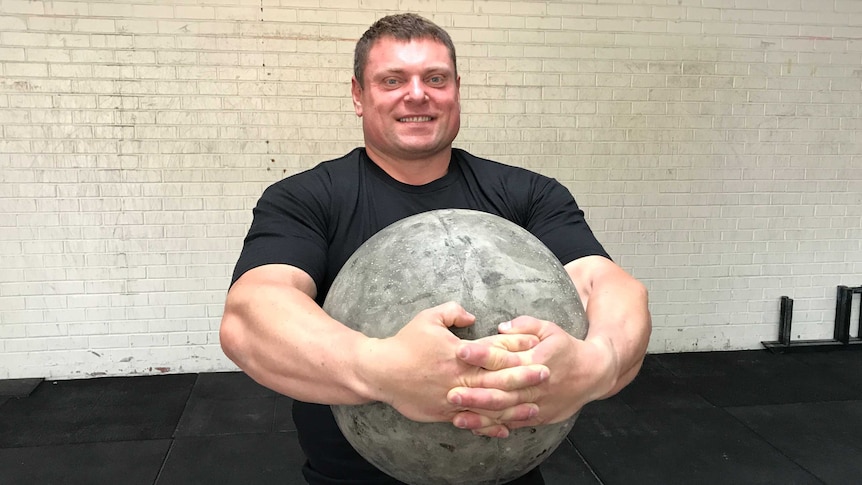 Strong Man Zydrunas Savickas holds an Atlas ball made of concrete.