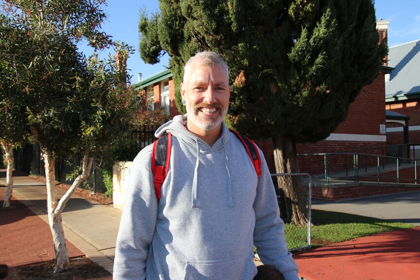 A smiling man outside a school