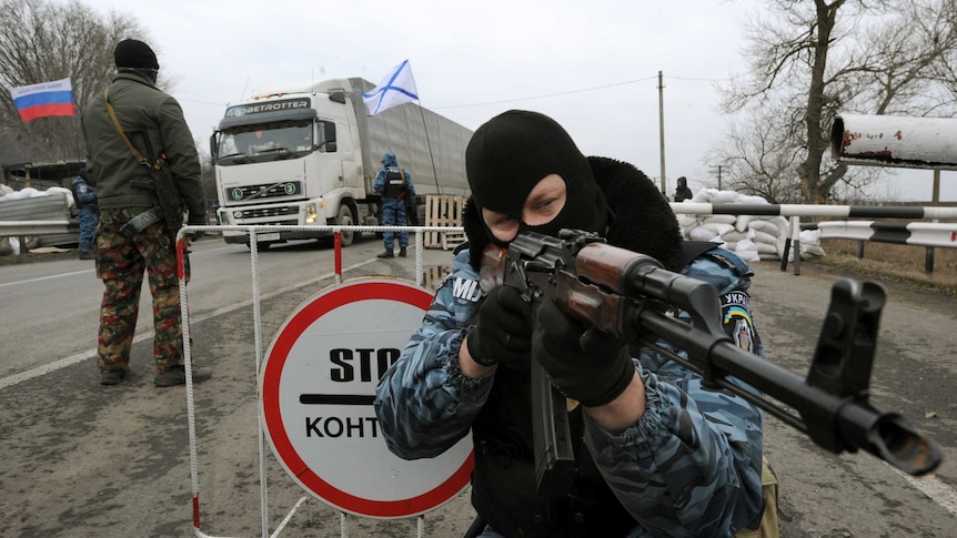 Ukrainian riot policeman aims his rifle