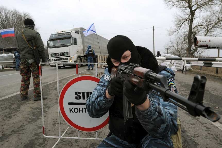 Ukrainian riot policeman aims his rifle