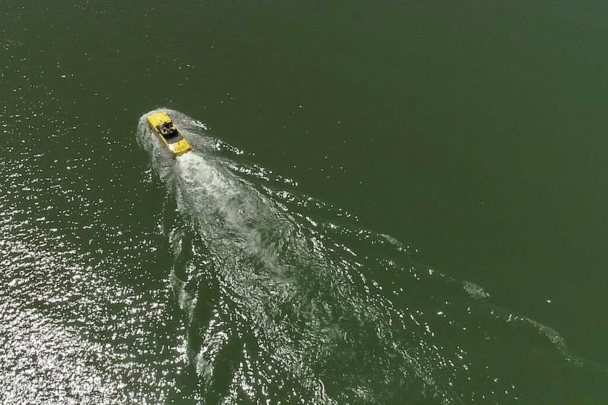 A seemingly normal car leaves a wake behind it as it motors around in a lake.