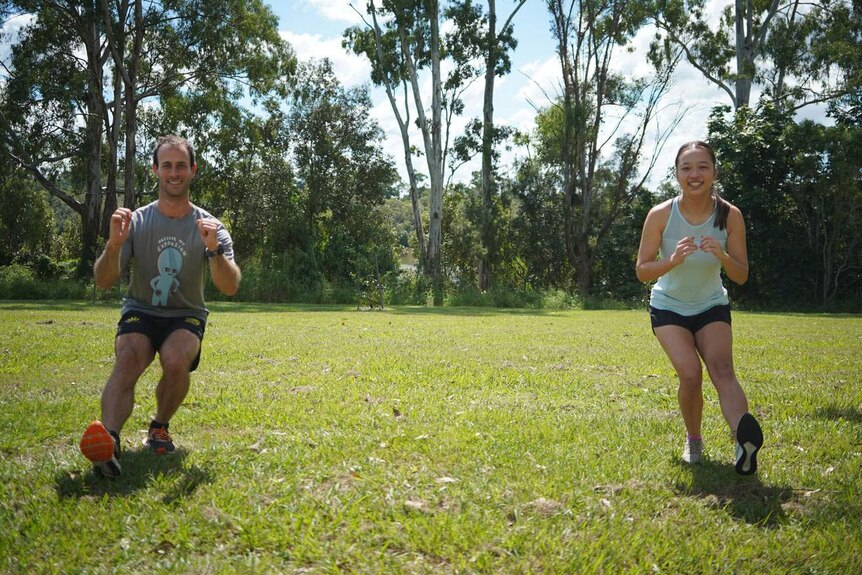Personal trainer John McNaughton with client Jasmin Lee exercise about two metres from each other in a Brisbane park.