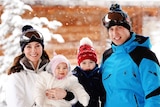 The royal family smiles with snow falling in the background