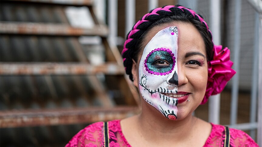 Rosa Cienfuegos stand outside wearing Day of the Dead skeleton make-up on half her face.