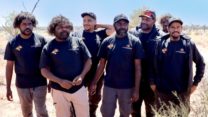 seven aboriginal men standing posing for a photo in the desert