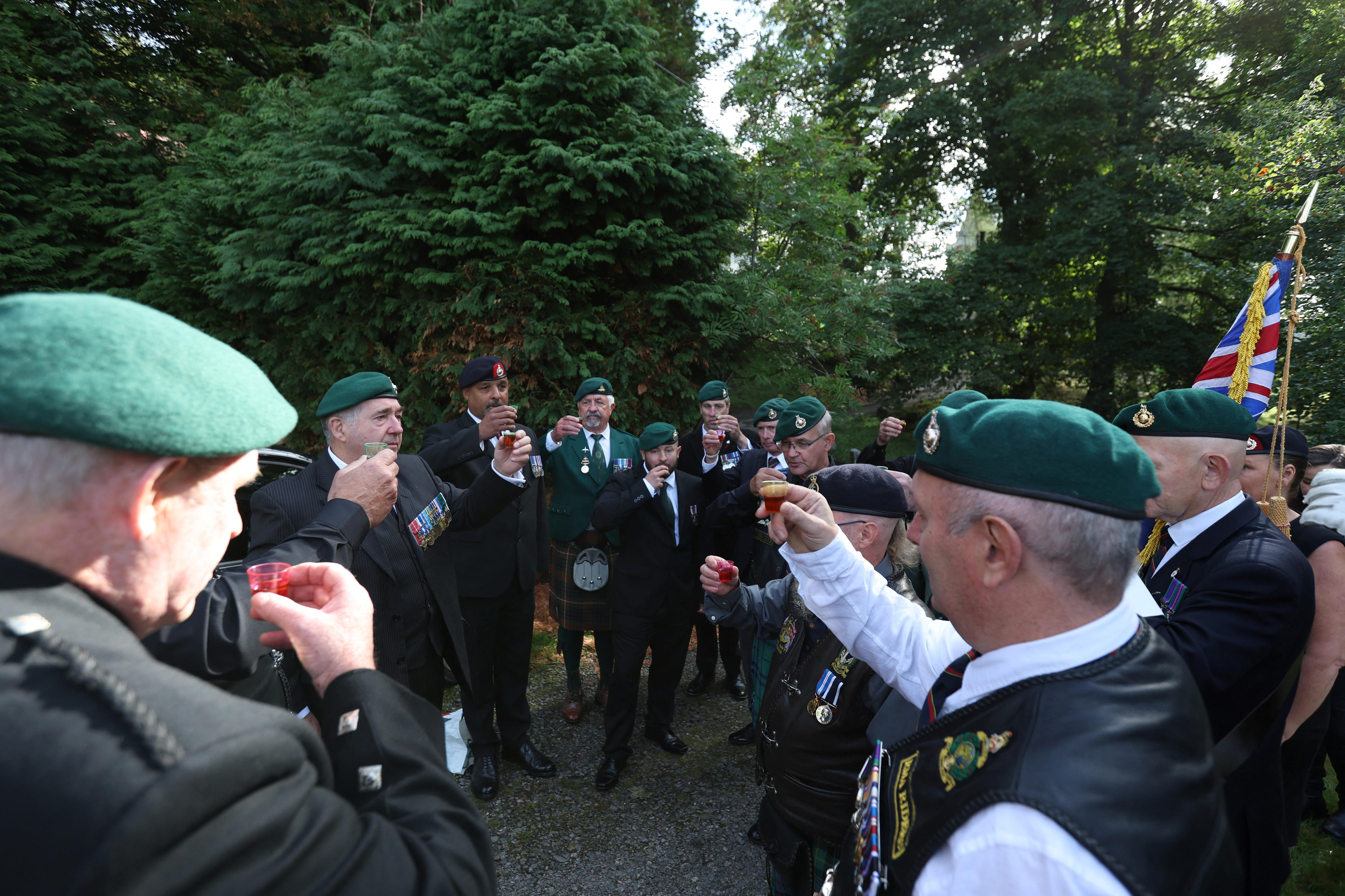 People in military uniforms raise a toast on a country road 
