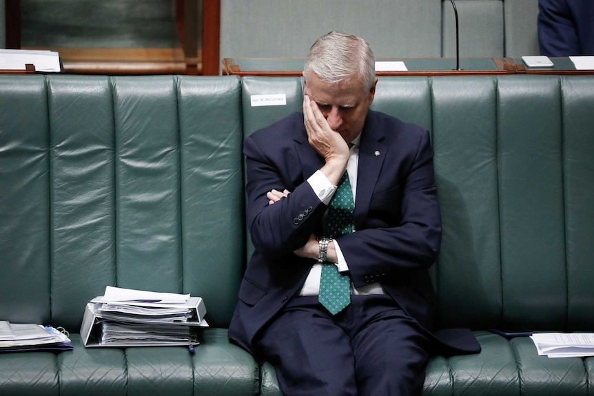 McCormack puts face into hand whilst sitting down on frontbench.