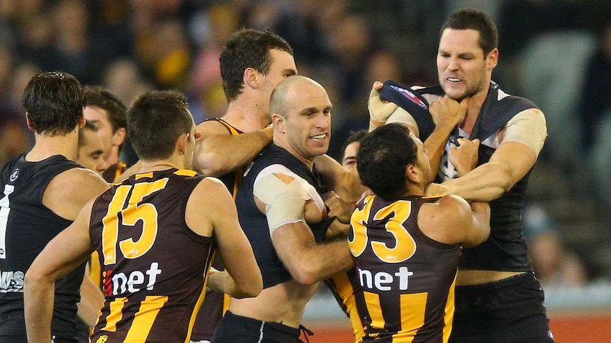 Difference of opinion ... Chris Judd (C) and Robert Warnock (R) wrestle with Cyril Rioli