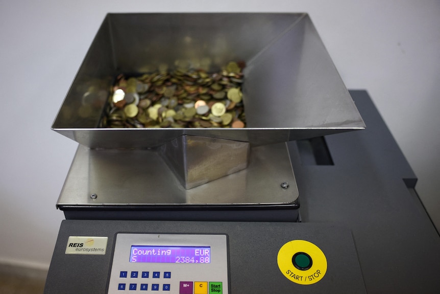 Coins are counted by an electronic machine. 