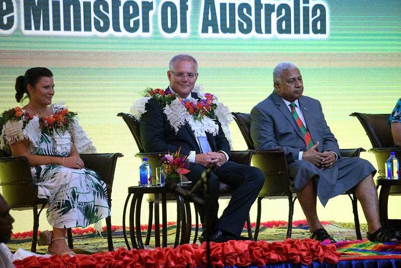 Scott Morrison sits on a stage with his wife Jenny and Fiji Prime Minister Frank Bainimarama