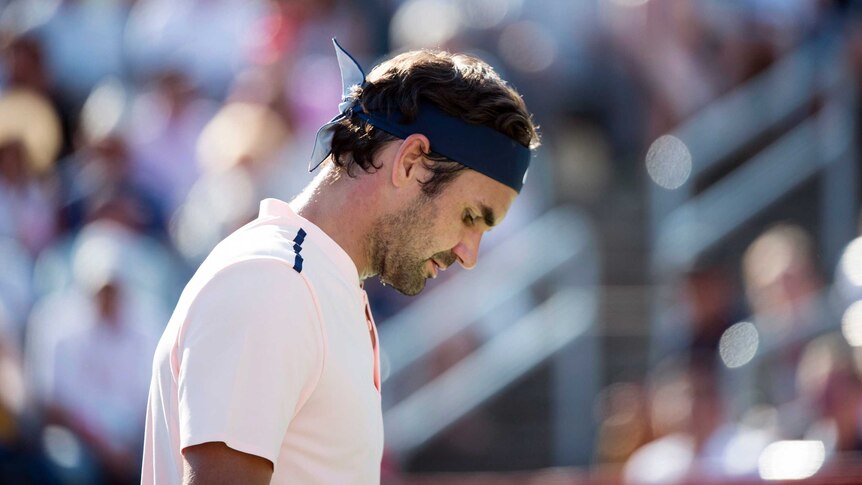 Roger Federer looks sad as he bows his head.
