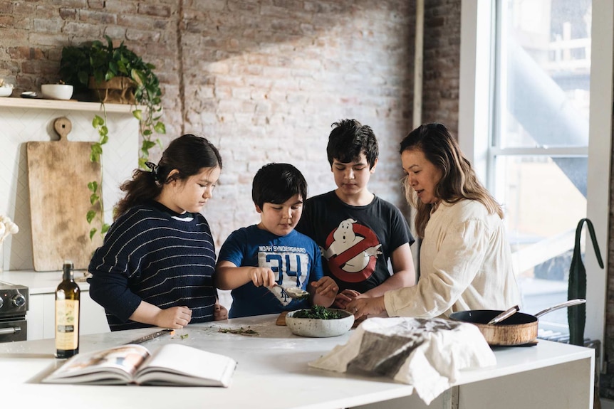 Hetty McKinnon in the kitchen with her three children, a daughter and two sons. They're preparing a vegetarian meal together.