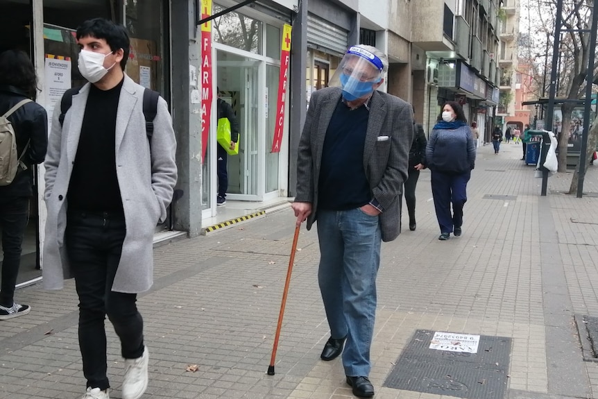 Elderly man with a walking stick in a city street in Chile.