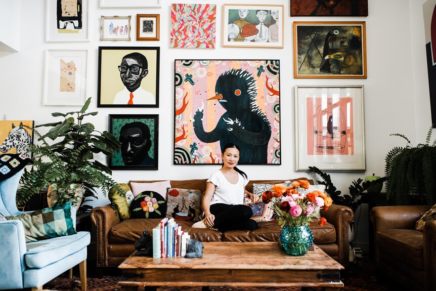 A woman poses for a portrait while surrounded by artwork and plants.