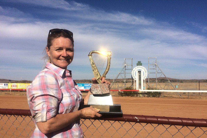 The trainer of the Outback Cup-winning horse It's Fred holds her trophy.