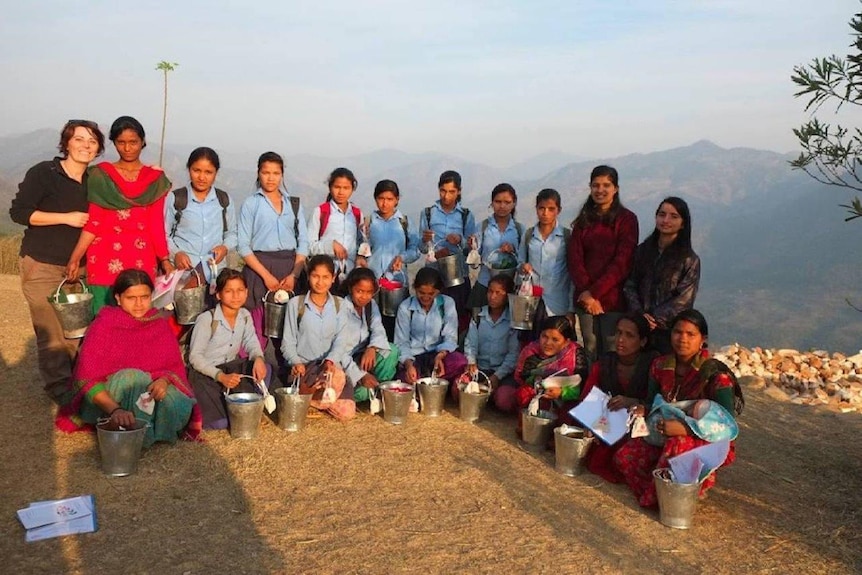 Row of girls holding buckets with cups inside