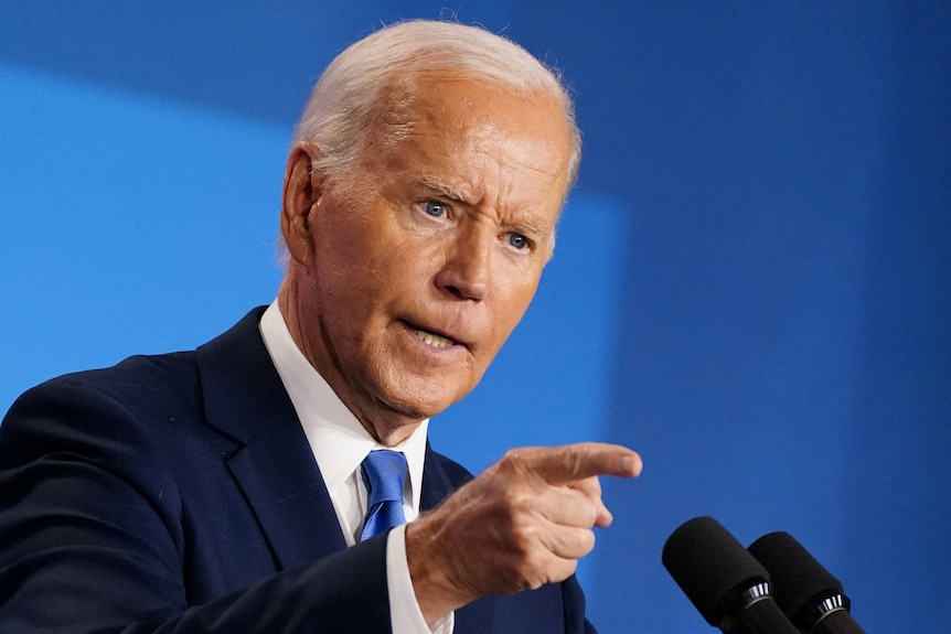 Joe Biden has a stern expression and points at something.