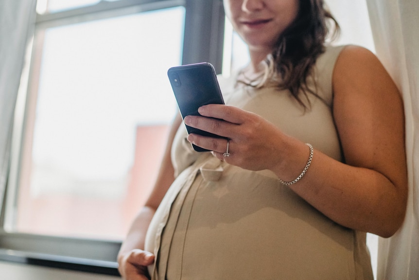 A pregnant woman using a mobile phone